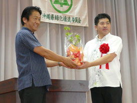 次期開催地、宜野座村の當眞村長に中山市長が苗木を贈呈した=20日午前、八島小