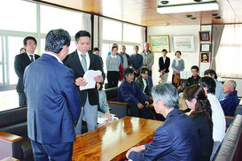 小規模幼稚園を休園させる方針の撤回を求め、市議会の知念辰憲議長に請願を提出する保護者や地域住民=13日