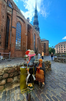 Woman knitting shawl in front of St. Peter's Church in Riga Old Town