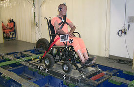 Crash-test dummy sits in a power wheelchair, which is secured on a sled