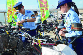 自転車に札を貼り付ける署員=16日、離島ターミナル