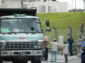 工事車両の近くで、プラカードを手に通行を妨害する基地反対派=8日午後、米軍キャンプ・シュワブ前