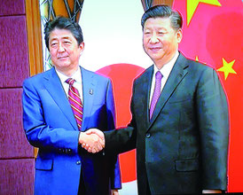 首脳会談で握手する習主席と安倍首相=中国国営テレビより