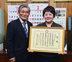 県知事賞を受賞した浦内さん(右)が我喜屋会長に受賞を報告した=11日、石垣市商工会館