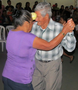 Pareja de adultos mayores del Cantón Jaramijó (Ecuador) baila con una naranja entre la frente de ambos.