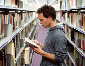 student mit buch in bibliothek