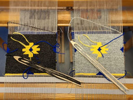 Deux grands coussins canapé à rayures exposés en plein air. Un coussin en rayures jaunes, oranges, marronnes, l'autre en rayures bleues, brunes et noires sur un fond de laine gris clair.