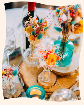 bouquet de fleurs séchées très colorées dans des vases bleus et jaunes posés sur des rondins de bois