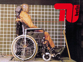 Ein Bild von einem im Rollstuhl sitzenden Dummy. Der Rollstuhl ist an einem speziellen Rollstuhlhalterungssystem mit dem Boden befestigt.