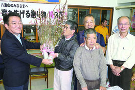 JTA八重山営業所の黒島所長(左端)から桃の花が贈呈された=23日午前、八重山育成園