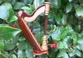 Mini-Harfe aus Holz vor grünem Ilex dekoriert.
