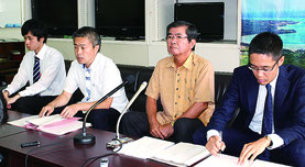 記者会見する高嶺館長(右から2人目)。後方に川平湾の拡大写真を掲示、記者会見後も自然保護の重要性などを報道陣に訴えた=17日、県庁