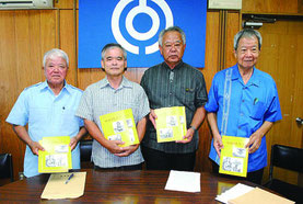 「白保の民話1、2」の発刊をアピールする石垣教育長(右から2人目)ら=12日午後、市教委