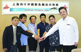 産業発展を目指し、手を合わせる関係者ら(写真右から仲栄真課長、玉城宏幸県衛生薬務課長、馬詰社長、環境科学センターの桑江善之副参事、総合事務局の島袋智志食料産業課長、平安名盛正県水産課長)