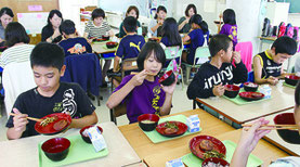 給食では「クーブイリチー」などが出され、児童らは伝統の味に笑顔を見せた=15日、曙小学校