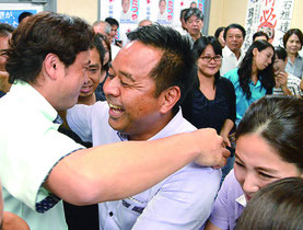 支持者らと抱擁を交わす石垣氏(中央)=9日夜、市内事務所