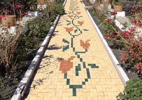 una combinacion de adoquines de piedra de distintos colores permite dibujar una flor en el camino del jardin