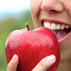 Nahaufnahme von Frau die in einen roten Apfel beißt.