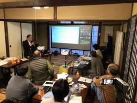 第一回速記茶話会　京都大学河原教授の講演風景です。プレゼン資料を表示したモニターの右側に、自動音声認識ソフトによる字幕を表示しています。