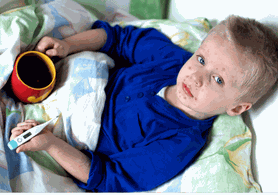 Ein Kind liegt krank im Bett. Er hat Pocken im Gesicht und einen Fieberthermometer in der Hand, so wie eine Tasse Tee.
