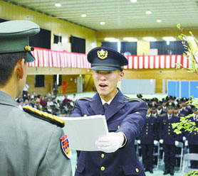 開連隊長(写真左)から修了証書を代表して授与される島袋候補生=24日、那覇駐屯地