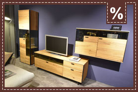 Wohnkombination aus Vitrine, TV Board und Hängeschrank aus hellem Holz vor einer lila Wand