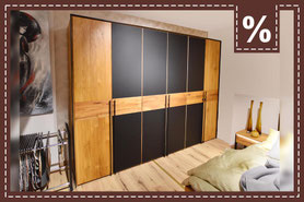 Großer Schrank aus Holz mit schwarzen Elementen in den Türen im Schlafzimmer. Prozentzeichen.