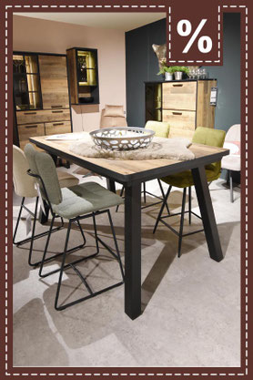 Holztisch mit schwarzen Beinen und sechs modernen Stühlen in Beige und Olivgrün. Prozentzeichen.