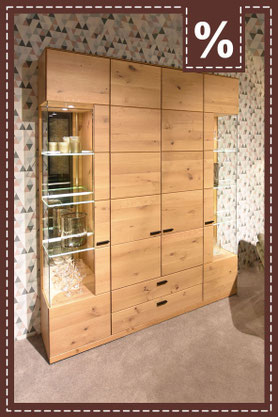 Sessel mit Fußhocker in creme vor einem dunkelgrauen Schrank