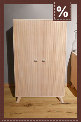 Kleiner Schrank aus hellem Holz mit vertikal gerillten Türen und ausgestellten Füßen. Prozentzeichen.