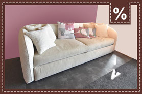 Großes helles Sofa mit 9 Kissen vor einer rosa Wand
