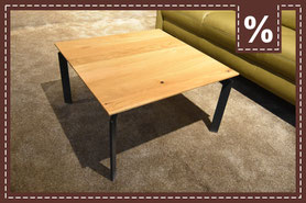 Quadratischer Couchtisch mit heller Holzplatte und schwarzen Metallbeinen. Prozentzeichen.