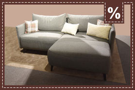 graues Ecksofa mit Querschläfer Funktion und karierten Kissen
