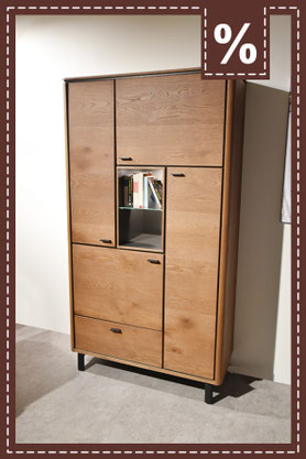 Brauner, quadratischer Sessel mit Armlehnen vor einem Holzbett. Prozentzeichen.