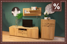 TV-Board und Kommode aus hellem Holz mit Regal vor grüner Wand und Uhr. Prozentzeichen.