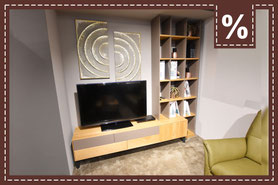 TV-Board aus Holz mit grauem Akzent mit passendem Regal und zwei goldenen Wandbildern. Prozentzeichen.