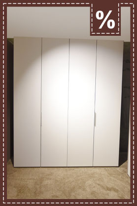 Großer, weißer, moderner viertüriger Kleiderschrank auf hellem Teppich. Prozentzeichen.