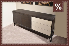 Dunkles Holz-Sideboard mit drei hellen Schubladen auf einem Teppich. Prozentzeichen.