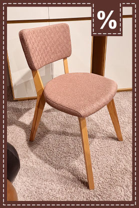 Gepolsterter, rosé farbener Stuhl mit ausgestellten Holzgestell. Prozentzeichen.