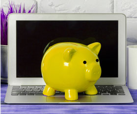 Laptop vor einer weißen Wand mit einem gelben Sparschwein