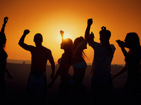 Tanzende Menschen in der Natur bei Sonnenuntergang