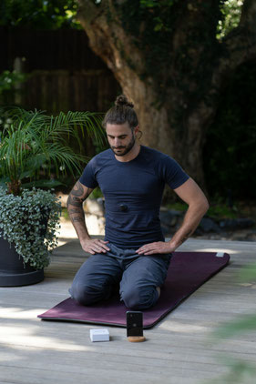 Mann auf Yoga-Matte am Meditieren im Grünen.