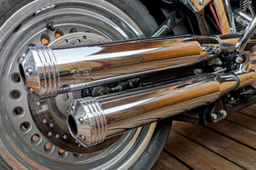 Nahaufnahme einer verchromten Auspuffanlage und des Hinterrads eines Motorrads