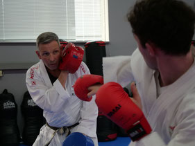 Trainer hält Pratze, während Karate-Schüler eine präzise Fausttechnik übt."