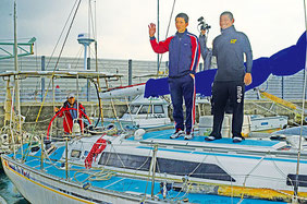 肌寒い風を受け、「安全航海で行ってきます」と元気に出港する前田船長(左端)と高校生=石垣港、午前10時過ぎ