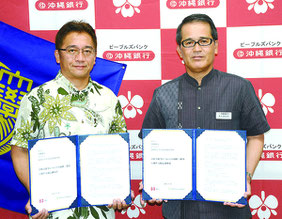 沖縄銀行と琉球大学大学院法務研究科との学修支援などで連携・協力する協定を結んだ沖縄銀行の保久盛長哲常務(右)と琉球大学大学院の吉﨑敦憲法務研究科長=16日、沖縄銀行本店(那覇市)