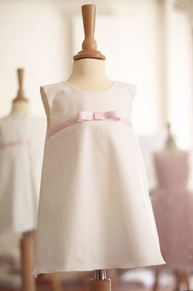 Robe cérémonie fille trapèze coton ivoire avec noeud rose. Atelier à Neuilly-sur-Seine. Envois dans toute la France.