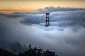 Die berühmte Golden Gate Bridge im dichten Nebel während des Sonnenaufgangs in San Francisco.