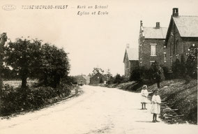 Oude foto met schoolgebouwen, een weg en twee kinderen. Zwart-wit foto.