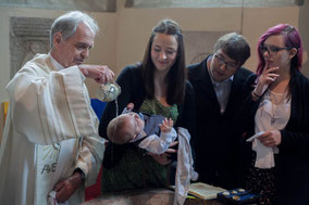 Frontalaufnahme der Taufe eines Babys mit Weihwasser auf der Stirn in der Kirche im Mühlviertel